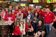 A diverse group of happy Indiana University alumni gathered at a bar.
